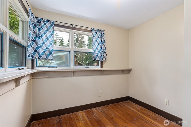spare room with baseboards and hardwood / wood-style floors