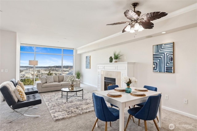 carpeted living area with ceiling fan, a fireplace, baseboards, and expansive windows
