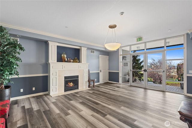 unfurnished living room with visible vents, ornamental molding, a large fireplace, and wood finished floors