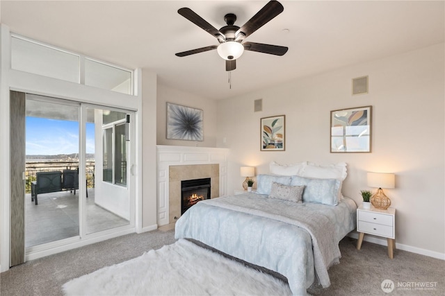 bedroom featuring a glass covered fireplace, baseboards, carpet, and access to exterior
