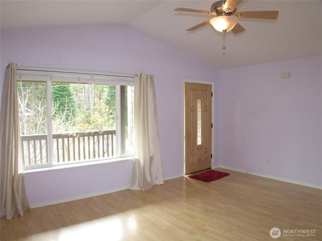 foyer entrance with a ceiling fan, vaulted ceiling, and wood finished floors
