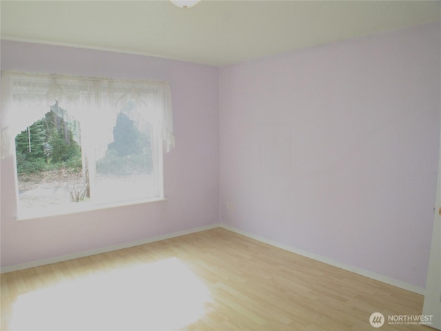 spare room with baseboards and wood finished floors