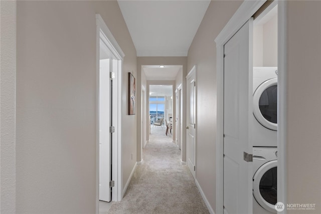 washroom featuring baseboards, light colored carpet, laundry area, and stacked washer / dryer