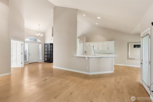 6719 Prairie Ridge Dr NE, Olympia, WA 98516 - unfurnished living room featuring light wood-type flooring, baseboards, high vaulted ceiling, and an inviting chandelier