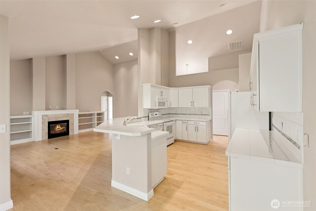6719 Prairie Ridge Dr NE, Olympia, WA 98516 - kitchen featuring visible vents, white cabinetry, white appliances, a peninsula, and a fireplace