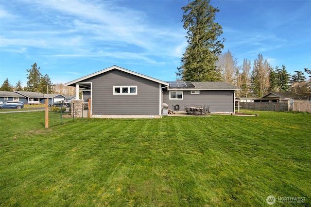 6473 Trigg Woods Ln, Ferndale, WA 98248 - back of house with roof mounted solar panels, a lawn, a patio, and fence