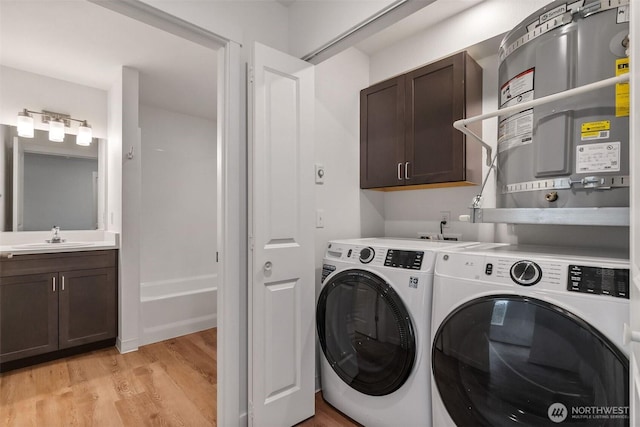 20107 Blair Ln, Rochester, WA 98579 - laundry room with independent washer and dryer, light wood-style flooring, a sink, strapped water heater, and cabinet space