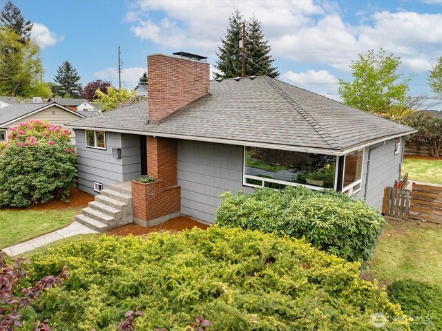 rear view of property with fence, a shingled roof, and a chimney