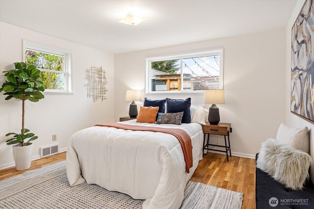 bedroom featuring baseboards, visible vents, multiple windows, and light wood-type flooring