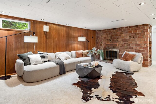 carpeted living area with recessed lighting, a fireplace, and wood walls