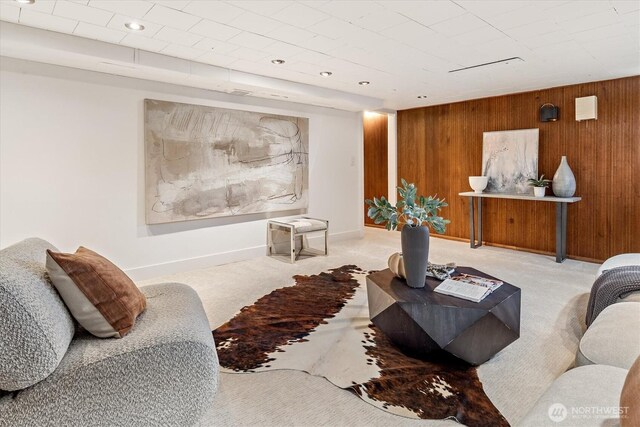 carpeted living room with baseboards and wood walls