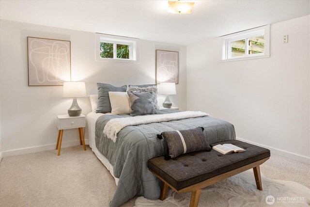bedroom featuring light colored carpet, baseboards, and multiple windows