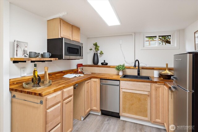 kitchen featuring light brown cabinetry, wood counters, appliances with stainless steel finishes, and a sink