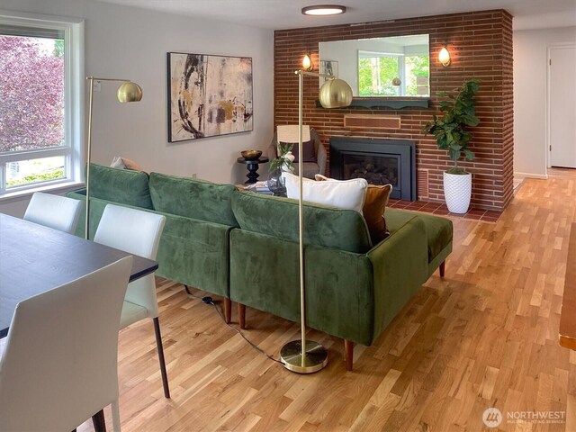 living room featuring a brick fireplace and wood finished floors