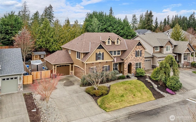 view of front of house featuring board and batten siding, a shingled roof, fence, stone siding, and driveway