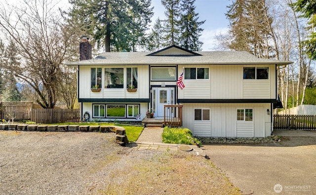 bi-level home with fence and a chimney