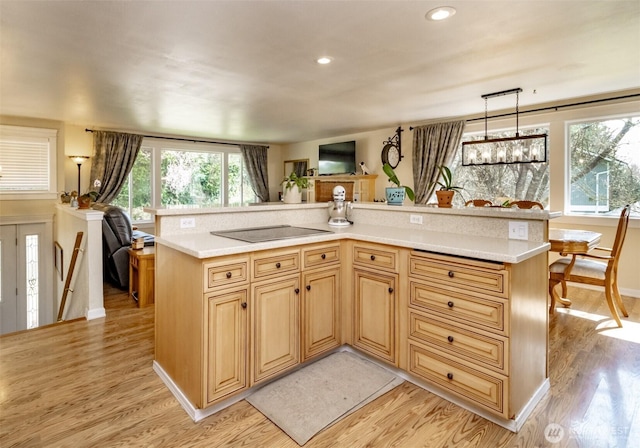 kitchen featuring light countertops, pendant lighting, black electric stovetop, and light wood-style flooring