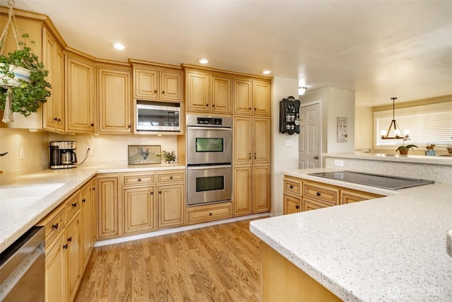 kitchen featuring light countertops, light wood finished floors, stainless steel appliances, recessed lighting, and a sink