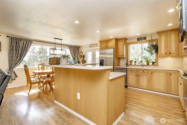 kitchen featuring light wood finished floors, a kitchen island, light countertops, and stainless steel appliances