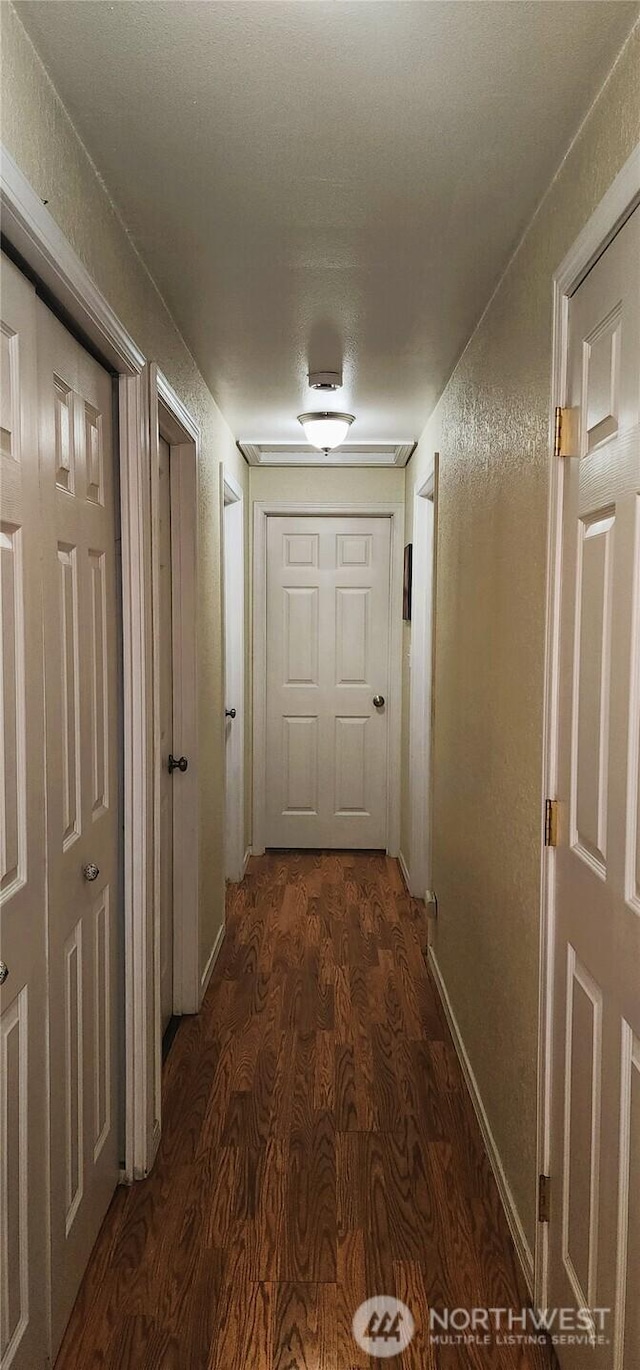 corridor with baseboards and dark wood-type flooring