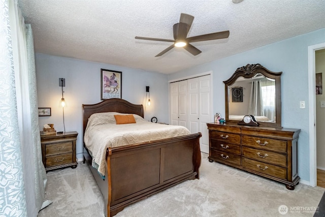 bedroom with light carpet, a closet, ceiling fan, and a textured ceiling