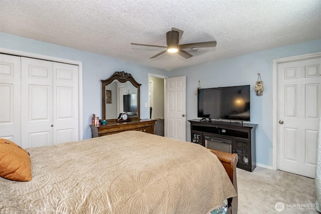carpeted bedroom featuring baseboards, a closet, ceiling fan, and a textured ceiling