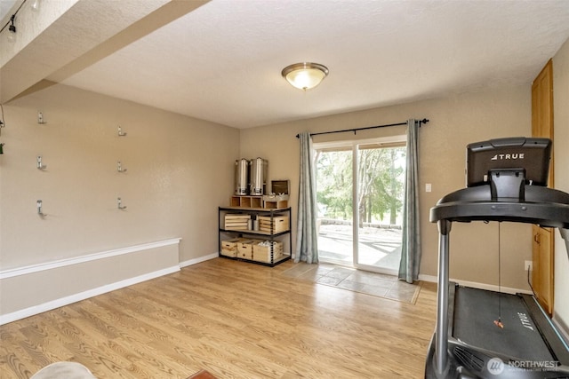 workout room with baseboards and light wood finished floors