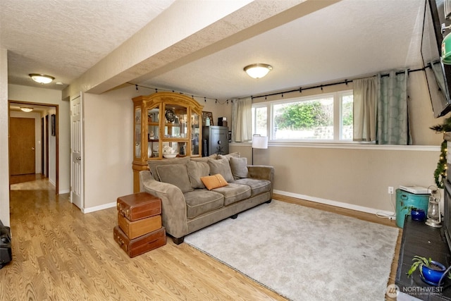 living room with a textured ceiling, baseboards, and wood finished floors