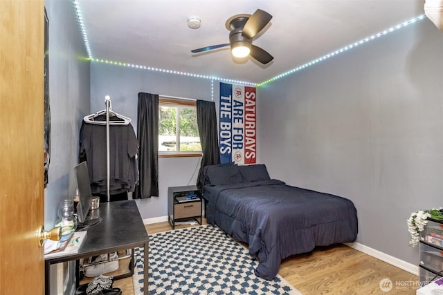 bedroom featuring baseboards, wood finished floors, and a ceiling fan