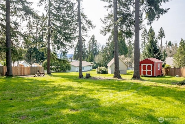 view of yard featuring a storage unit, a fenced backyard, and an outdoor structure