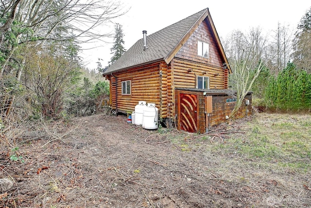view of home's exterior featuring log siding and roof with shingles