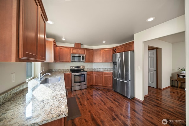 kitchen featuring dark wood finished floors, a sink, light stone counters, stainless steel appliances, and recessed lighting