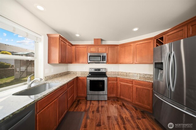 kitchen featuring appliances with stainless steel finishes, light stone countertops, dark wood finished floors, a sink, and recessed lighting