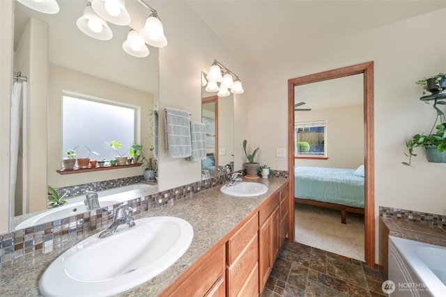 ensuite bathroom with a sink, a garden tub, double vanity, and a notable chandelier
