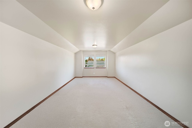 bonus room featuring baseboards, vaulted ceiling, and light carpet