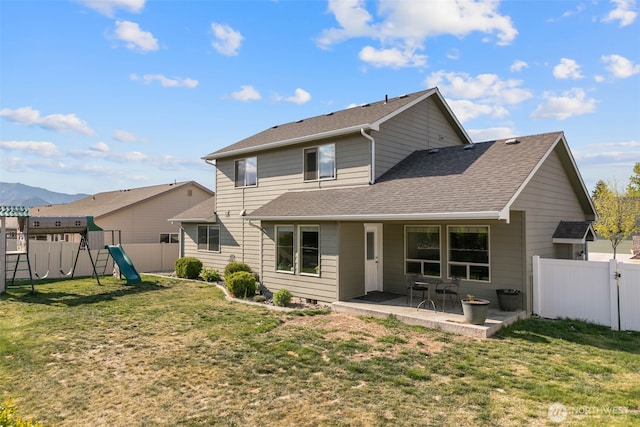 rear view of house with a patio, a fenced backyard, a playground, and roof with shingles