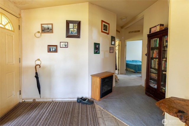 carpeted foyer entrance with lofted ceiling and visible vents
