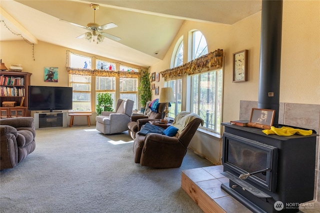 living room featuring a wood stove, a ceiling fan, lofted ceiling, and carpet floors