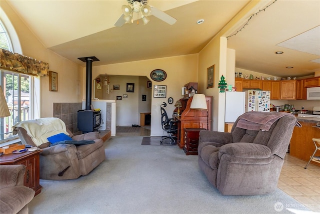 living room featuring a ceiling fan, light carpet, a wood stove, vaulted ceiling, and recessed lighting