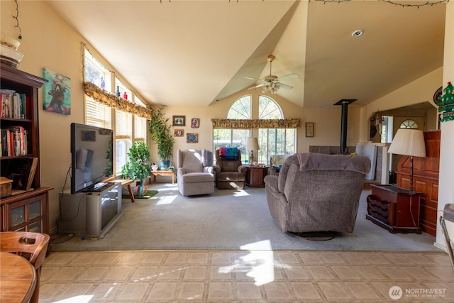 living room with a wood stove, carpet, a ceiling fan, and a healthy amount of sunlight