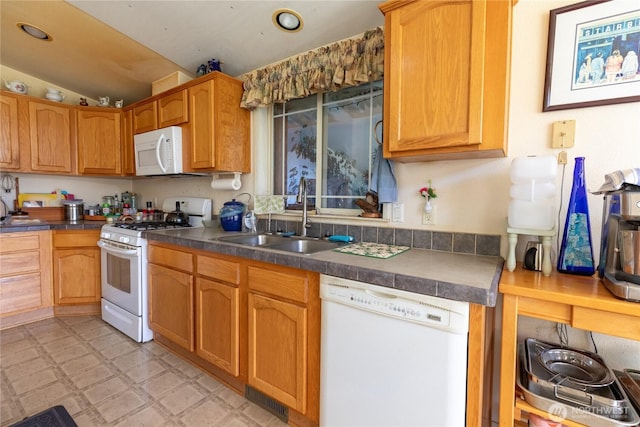 kitchen featuring a sink, dark countertops, light floors, visible vents, and white appliances