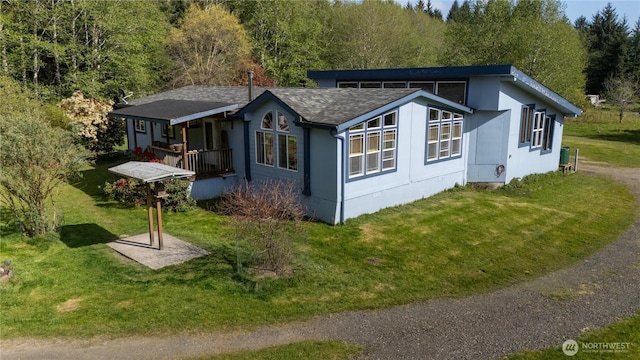 exterior space with a yard, a shingled roof, and a porch