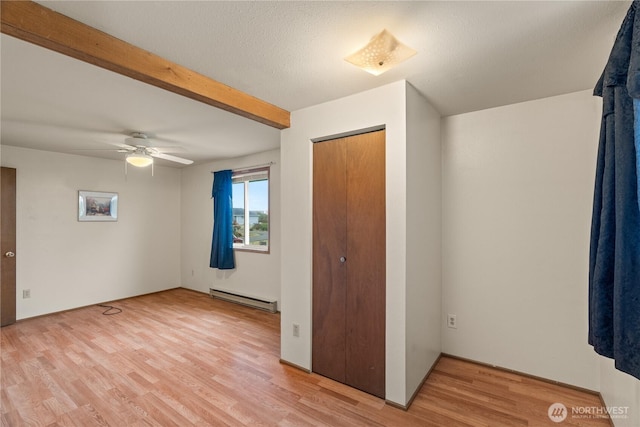 1205 Fairwood Dr SW, Ocean Shores, WA 98569 - unfurnished bedroom featuring light wood finished floors, ceiling fan, a closet, a baseboard heating unit, and beamed ceiling
