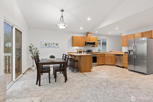 kitchen featuring stainless steel appliances, vaulted ceiling, a peninsula, recessed lighting, and light countertops