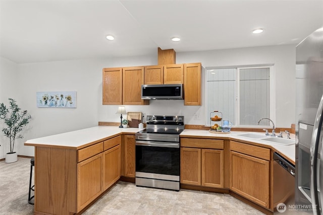 kitchen featuring stainless steel appliances, a sink, a peninsula, light countertops, and recessed lighting