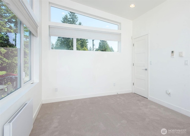 carpeted empty room with recessed lighting, baseboards, and radiator heating unit