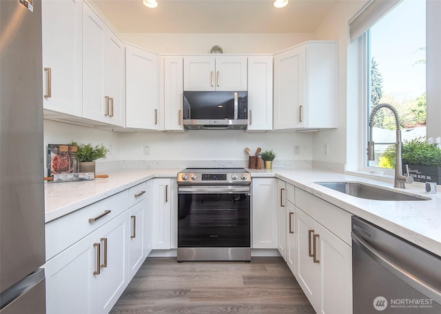 kitchen featuring stainless steel appliances, recessed lighting, white cabinetry, and a sink