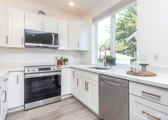 kitchen featuring a sink, white cabinetry, appliances with stainless steel finishes, and light stone countertops