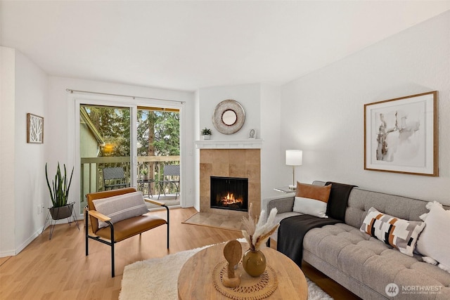 living room with baseboards, light wood-type flooring, and a tile fireplace