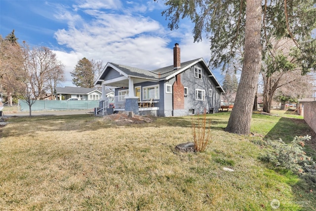 exterior space with a yard, fence, covered porch, and a chimney